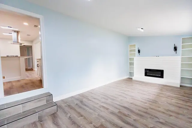 a view of a livingroom with wooden floor and a fireplace