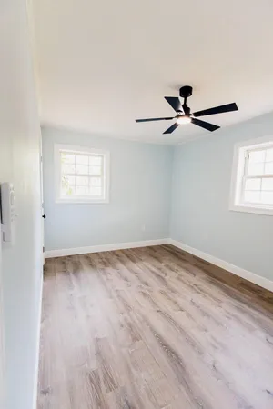 a view of empty room with wooden floor and fan
