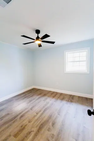 a view of an empty room with wooden floor and a window