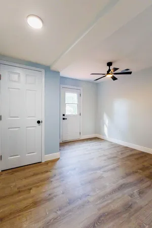 an empty room with wooden floor closet and windows