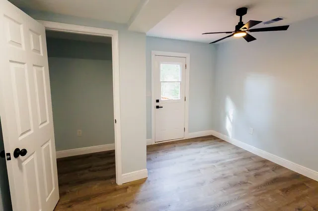 an empty room with wooden floor mirror and windows