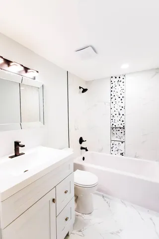 a bathroom with a bathtub shower sink vanity and toilet