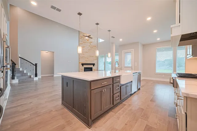 a large kitchen with a large counter top space a sink stainless steel appliances and windows