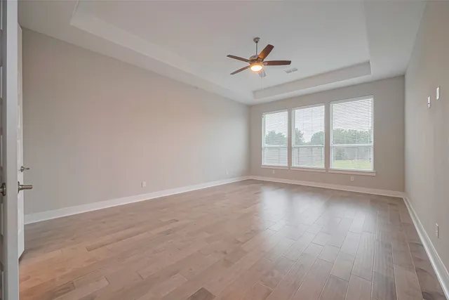 a view of an empty room with wooden floor and a window