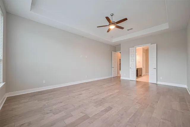 a view of an empty room with wooden floor and windows