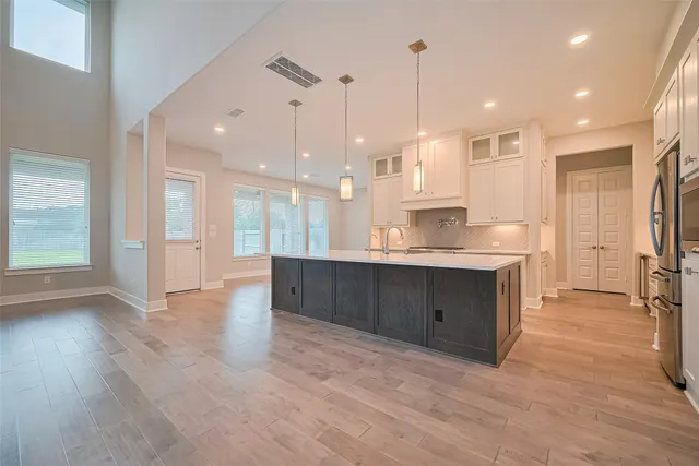 a large kitchen with stainless steel appliances kitchen island a large counter top and wooden floors