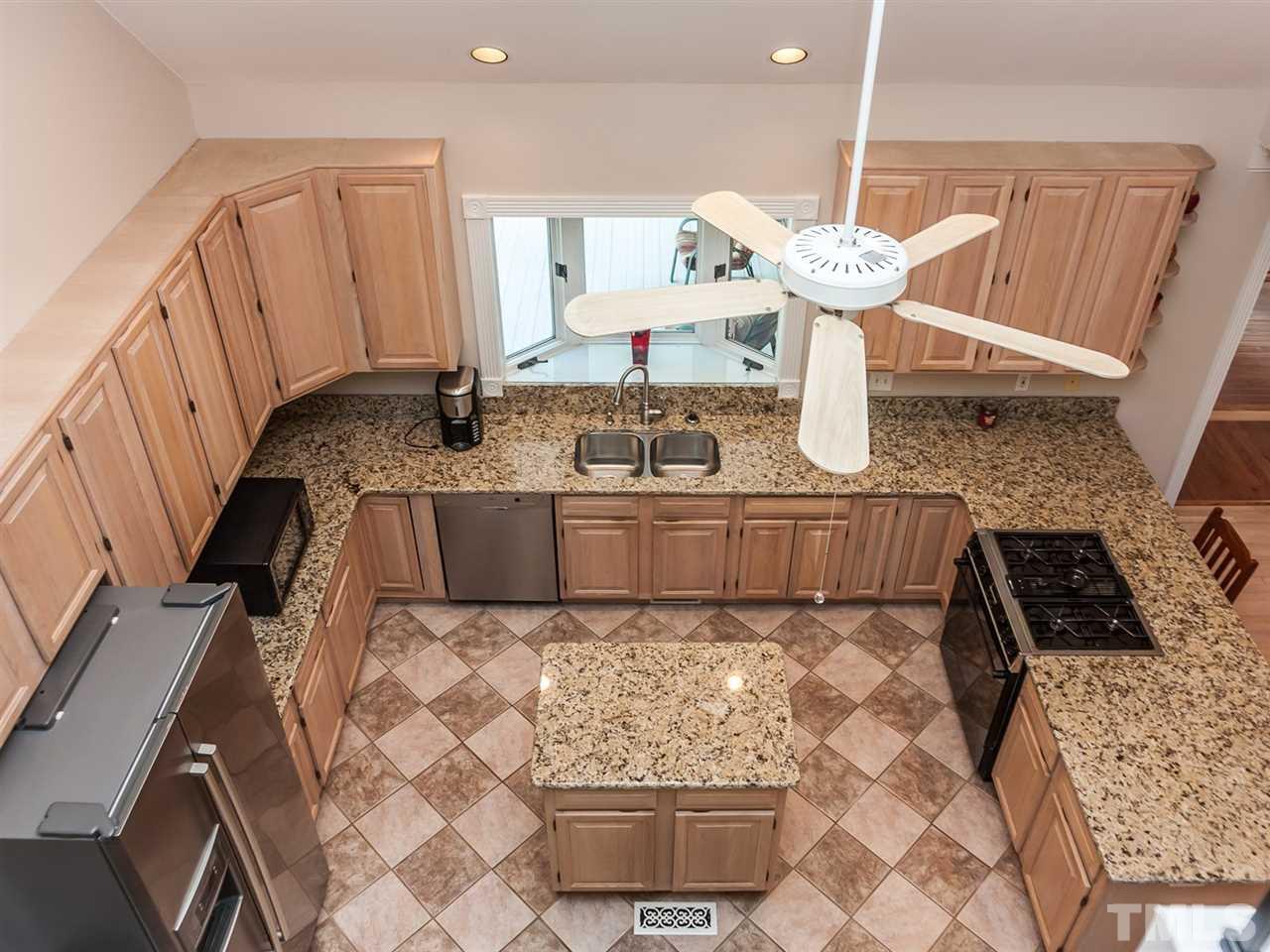 3128 Sanders Road Willow Spring, NC 27592 - Photo 6 of 25 a kitchen with kitchen island granite countertop a stove and a sink