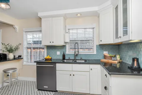a kitchen with a sink a stove a window and cabinets