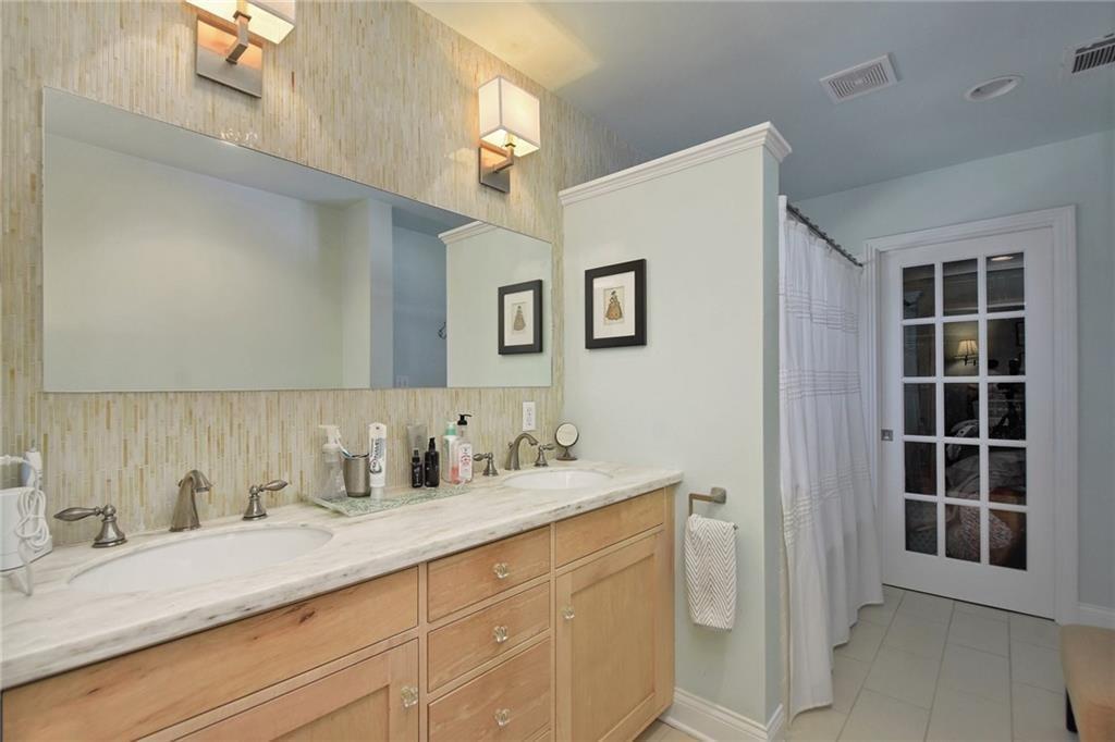 4412 Barrow Avenue, Unit A Austin, TX 78751 - Photo 17 of 28 Bathroom with a shower with shower curtain, double vanity, light tile patterned floors, and decorative backsplash