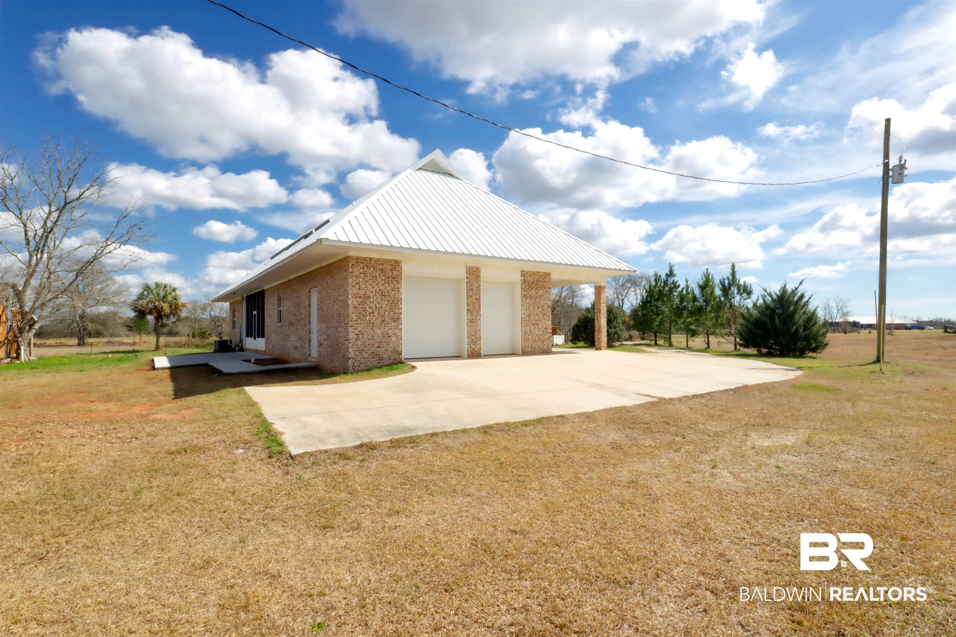 28461 Gardner Road Elberta, AL 36530 - Photo 37 of 46 View of side of home with brick siding, a lawn, a metal roof, and concrete driveway