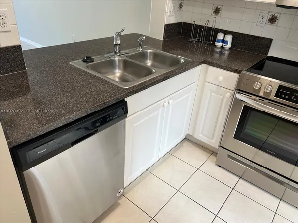 a kitchen with granite countertop a sink dishwasher stove and cabinets