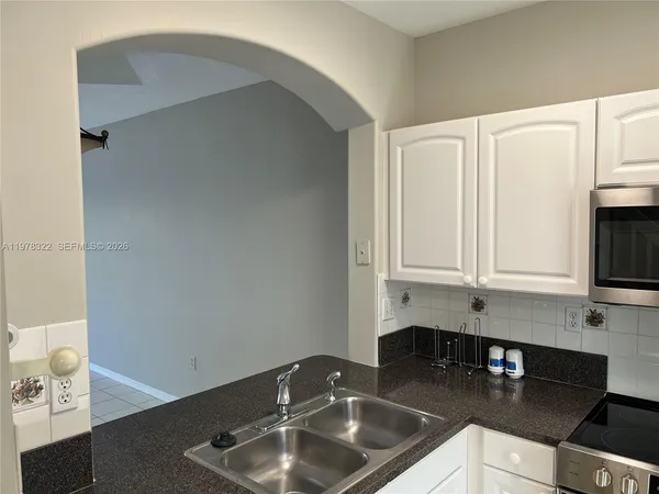 a kitchen with sink a microwave and cabinets