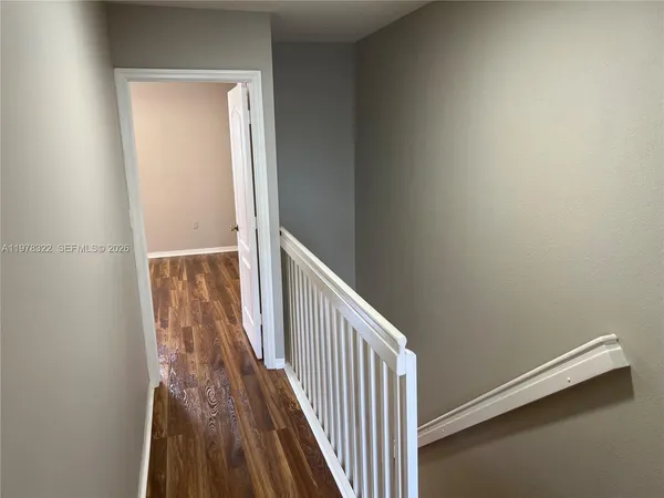 a view of a hallway with wooden floor and staircase