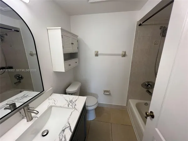 a bathroom with a granite countertop bathtub shower and toilet
