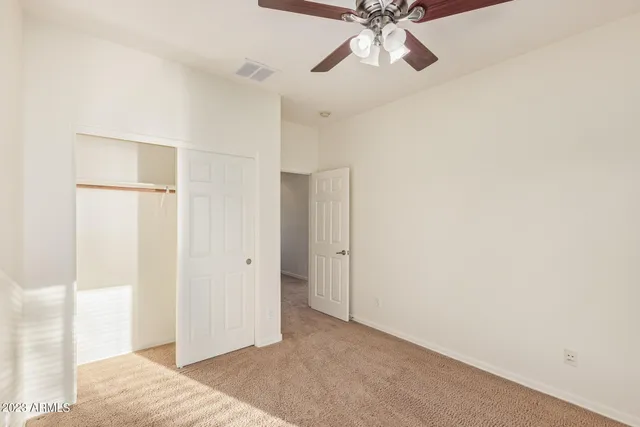 an empty room with windows and fan