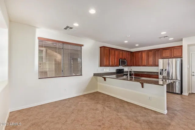 a large white kitchen with stainless steel appliances a large window and a fireplace