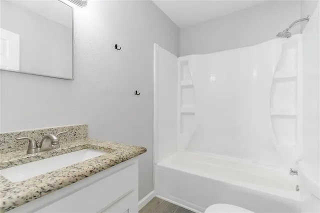 a bathroom with a granite countertop bathtub sink vanity and toilet