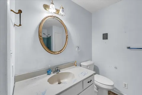 a bathroom with a toilet sink vanity and mirror