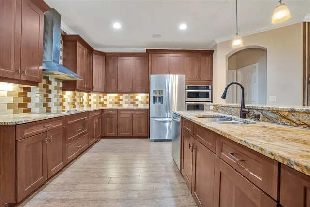 a kitchen with stainless steel appliances granite countertop a sink a stove and a wooden floors