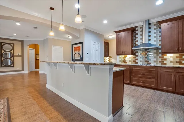 a kitchen with stainless steel appliances granite countertop a refrigerator a sink dishwasher and wooden cabinets with wooden floor