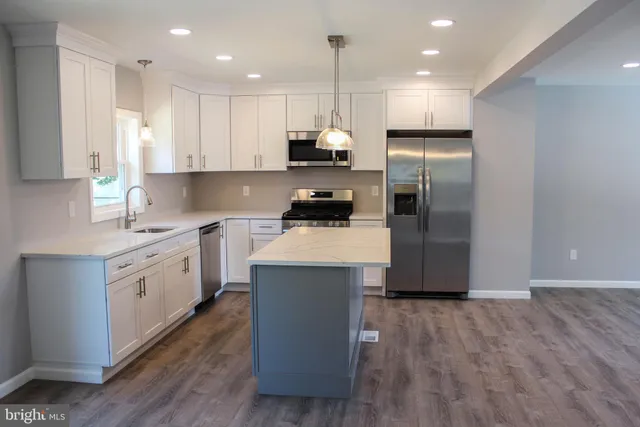 a kitchen with kitchen island a white cabinets and stainless steel appliances