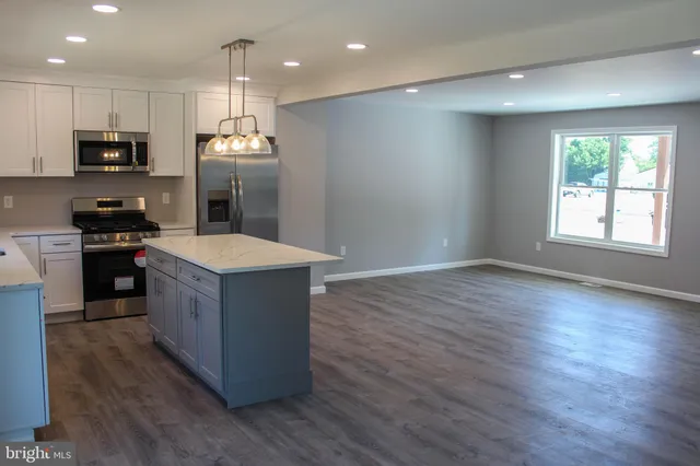 a kitchen with stainless steel appliances kitchen island granite countertop a stove a sink a refrigerator and a microwave