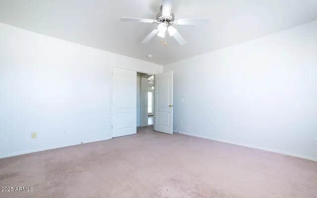 an empty room with windows and ceiling fan