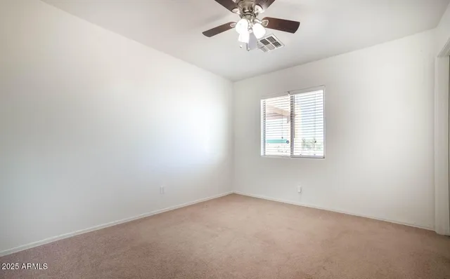 an empty room with a window and a fan