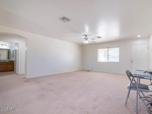 an empty room with chandelier fan and windows