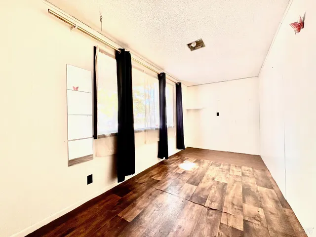 a view of an empty room with kitchen and a window