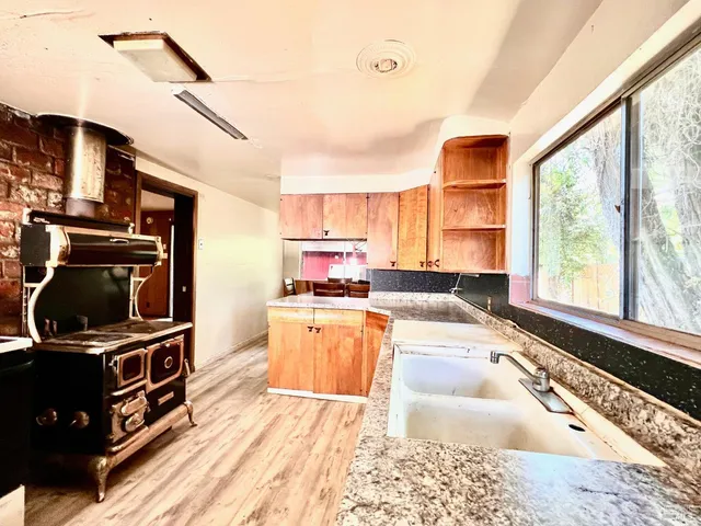 a living room with stainless steel appliances kitchen island granite countertop a refrigerator a stove a sink dishwasher with a dining table and chairs with wooden floor