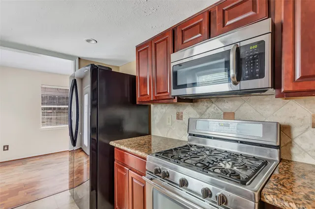 a kitchen with stainless steel appliances granite countertop a stove a microwave and a refrigerator