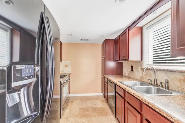a kitchen with stainless steel appliances granite countertop a refrigerator a sink and wooden cabinets