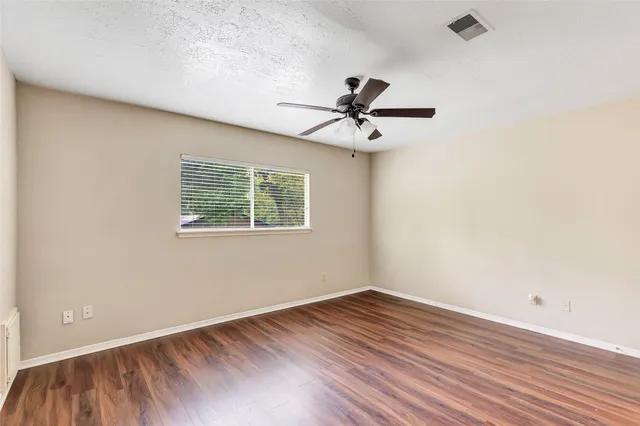 a view of a big room with wooden floor and windows