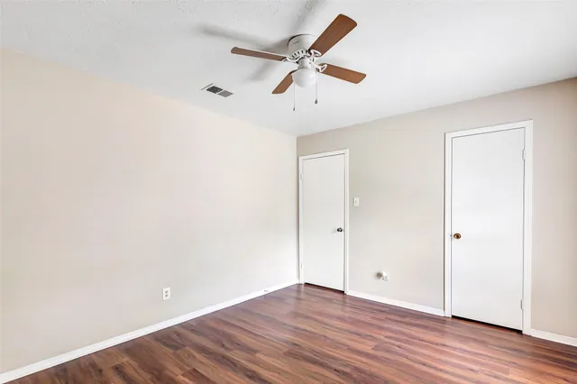 an empty room with wooden floor and a ceiling fan
