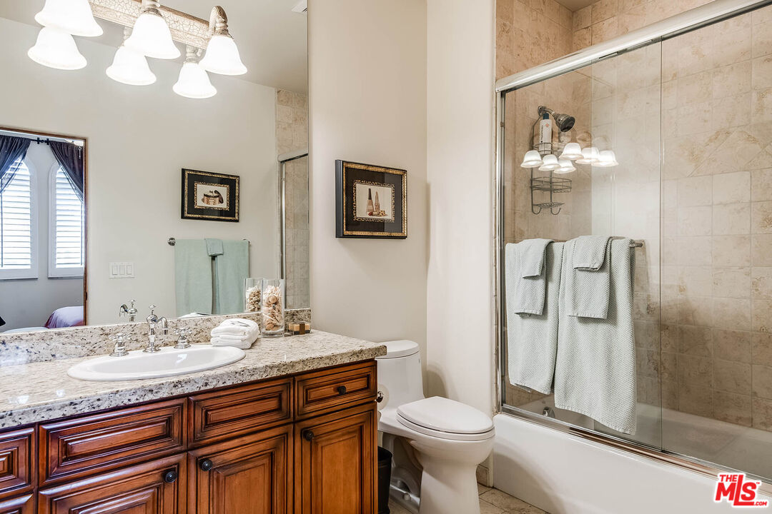 4520 Tyrone Avenue Sherman Oaks, CA 91423 - Photo 48 of 61 a bathroom with a granite countertop sink a toilet and a mirror