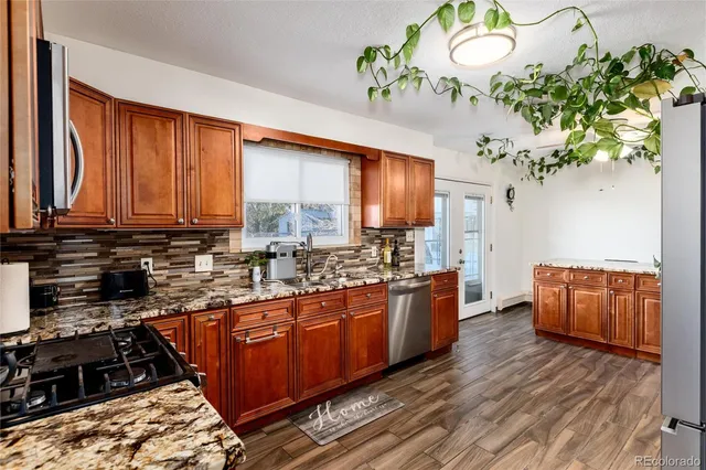 a kitchen with stainless steel appliances granite countertop a stove a sink dishwasher and a refrigerator