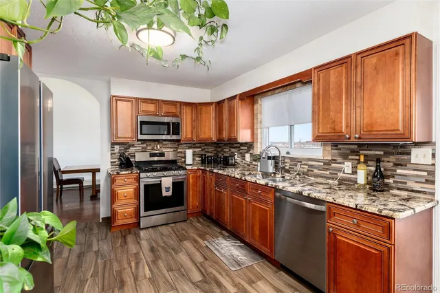 a kitchen with stainless steel appliances granite countertop wooden cabinets a stove top oven a sink and dishwasher