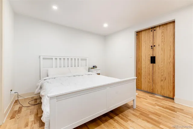 a spacious bedroom with a bed and wooden floor