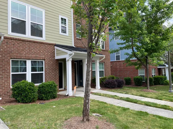 a view of a brick house with a yard and large trees