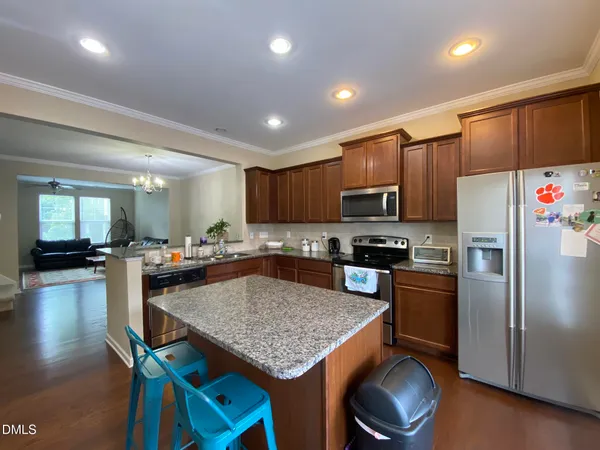 a kitchen with stainless steel appliances granite countertop a stove refrigerator a oven a sink a dining table and chairs with wooden floor