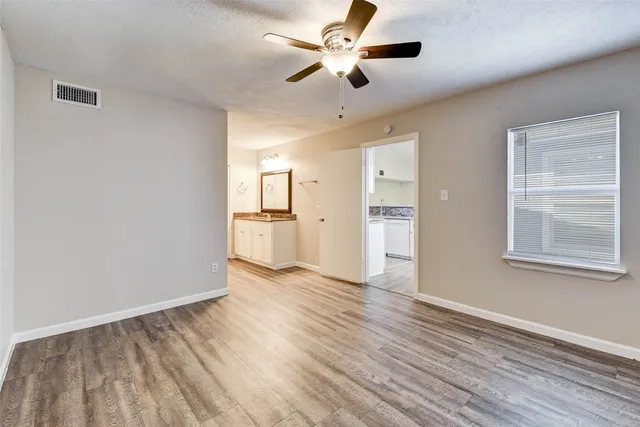 a view of an empty room with window and wooden floor