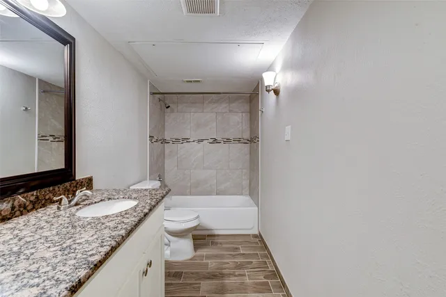 a bathroom with a granite countertop sink a toilet and shower