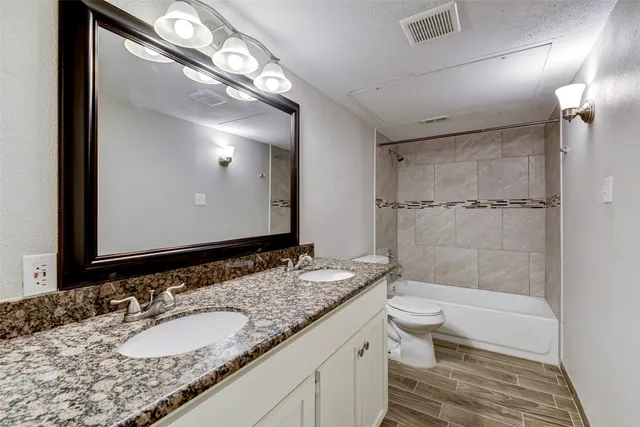 a bathroom with a granite countertop sink toilet and shower