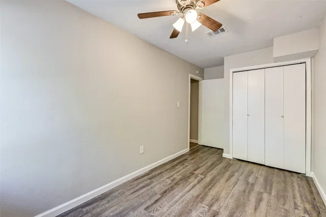 wooden floor in an empty room with a chandelier fan