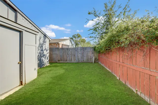 a view of a backyard with wooden fence and large trees