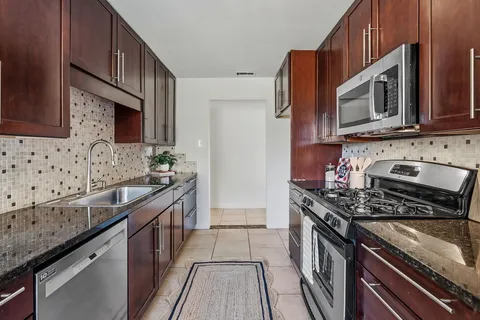 a kitchen with stainless steel appliances granite countertop a stove microwave and sink