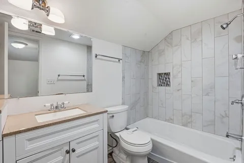 a bathroom with a granite countertop sink a toilet and shower
