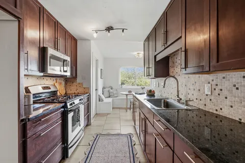 a kitchen with stainless steel appliances granite countertop a sink stove and cabinets