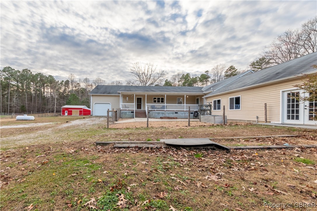 Rear view of house with a porch, a garage, and an outbuilding